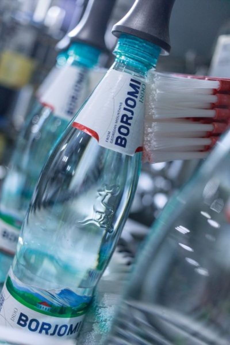Pro Flasche werden drei Kaltleim-Papieretiketten an Bauch, Brust und Rücken exakt am Logo-Embossing ausgerichtet (Bild: Frank Reinhold).