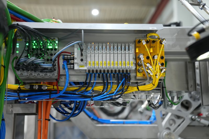 Platz im Schaltschrank: Ein an das PNOZmulti 2 angeschlossenes PDP-Link Modul verarbeitet in einem Strang bis zu vier Feldverteiler. Die Umverpackungsanlage benötigt lediglich ein Kabel aus dem Schaltschrank, um 16 PSENslock 2 anzusteuern und auszuwerten (Bild: Pilz).