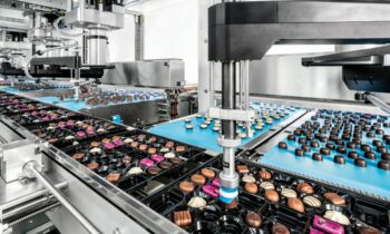 Sechs 4-Achs-Roboter greifen die Pralinen von jeweils zwei Zuführbändern und platzieren sie in Trays (Bild: Schubert).