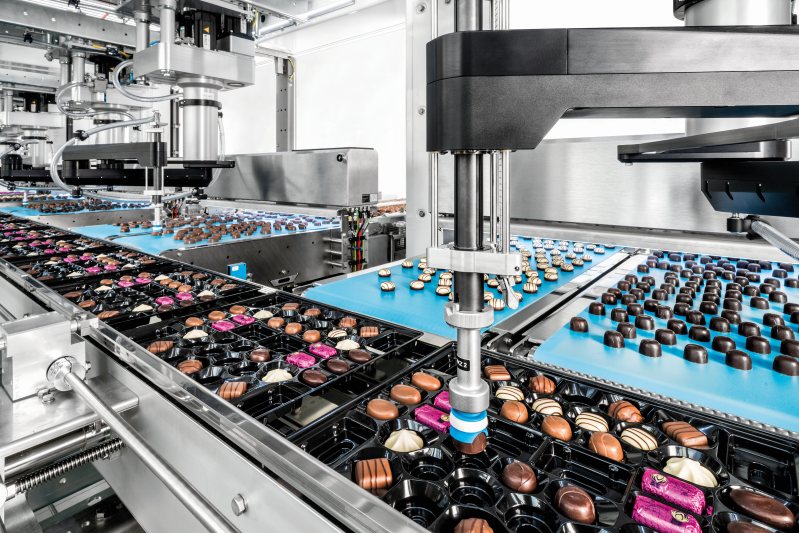 Sechs 4-Achs-Roboter greifen die Pralinen von jeweils zwei Zuführbändern und platzieren sie in Trays (Bild: Schubert).